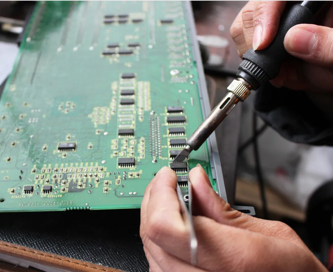 The technicians of REACO CNC are soldering the chips on the Fanuc circuit board.