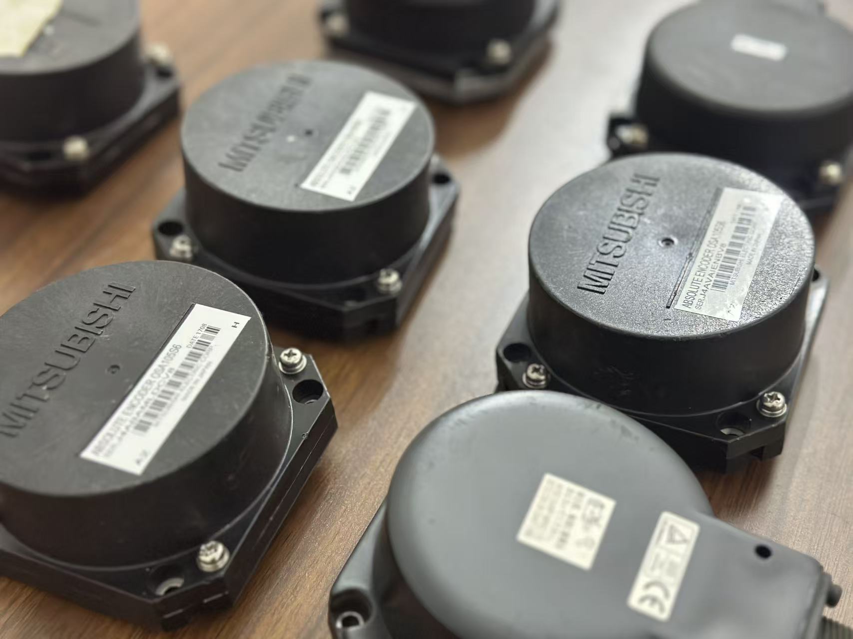 Background image showing Mitsubishi CNC encoder units used for precise motion feedback in automation systems