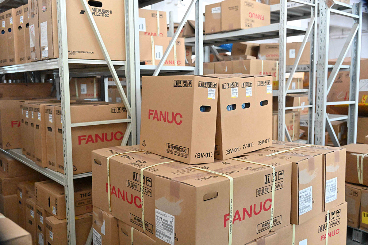 Warehouse shelves filled with boxed FANUC CNC parts, showing Reaco CNC’s large inventory for fast global delivery.